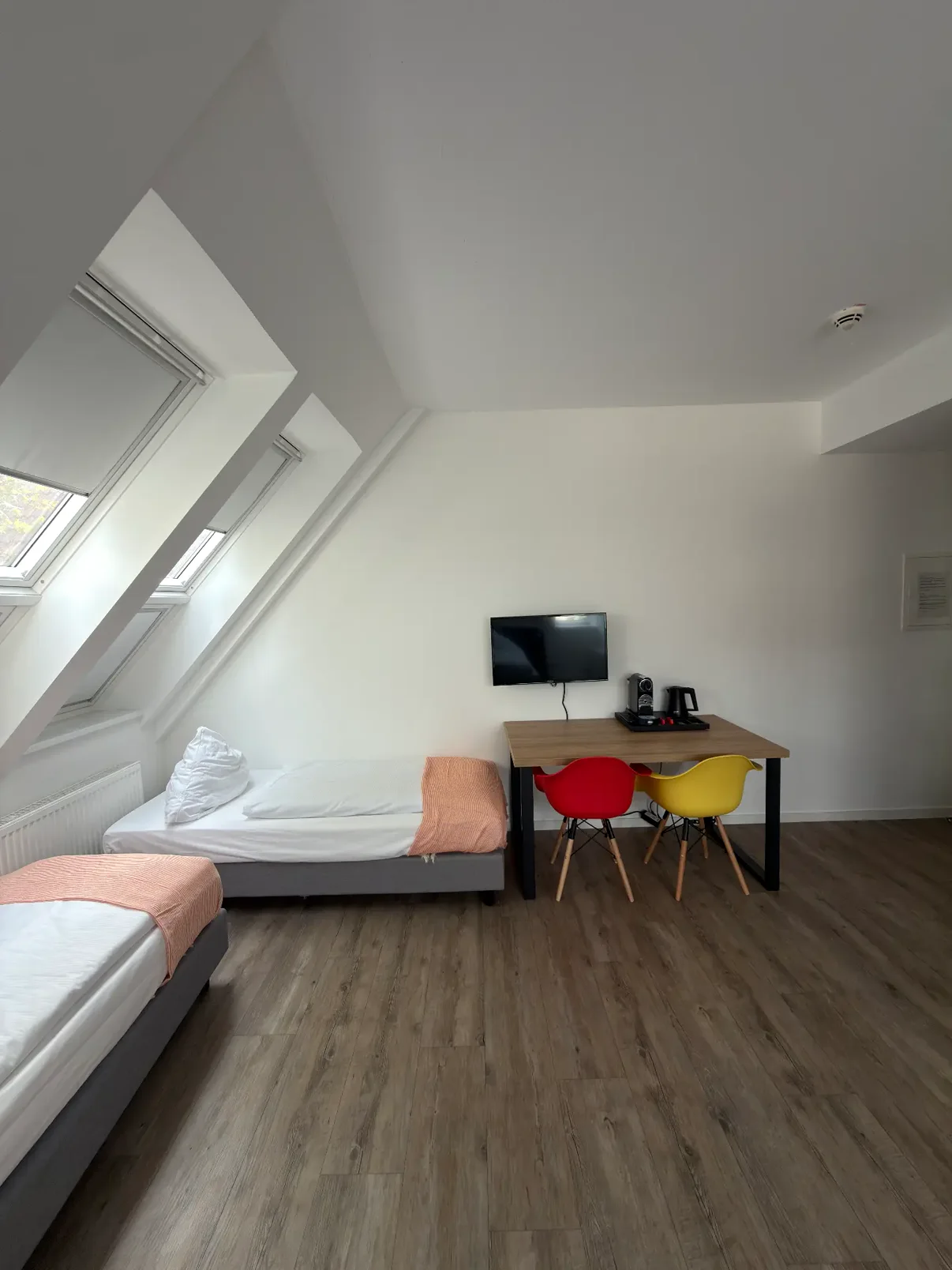 Zwei Einzelbetten unter Dachfenstern neben dem Arbeitstisch mit Fernseher