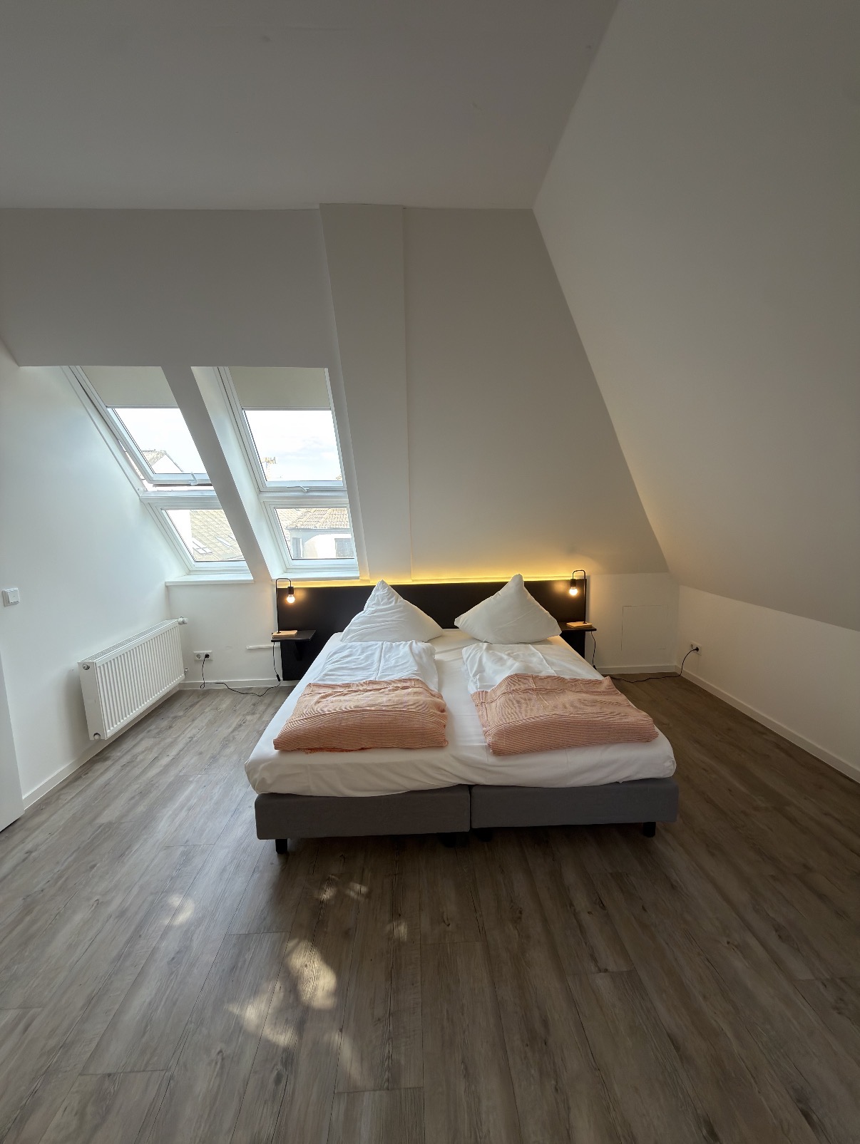 Doppelbett unter der Dachschräge mit Blick auf die Fenster