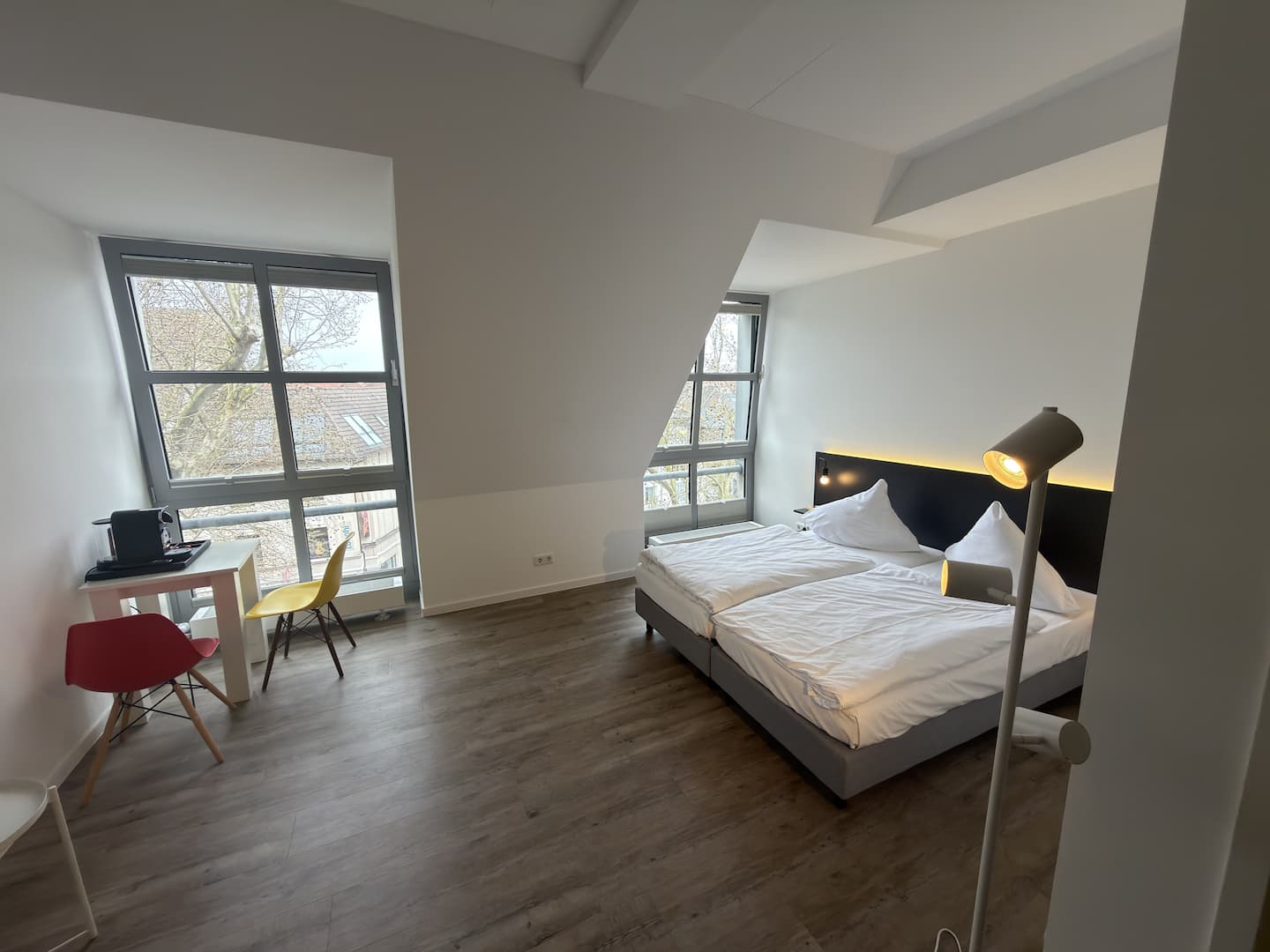 Doppelbett mit Stehlampe und Fenstern zur Straße