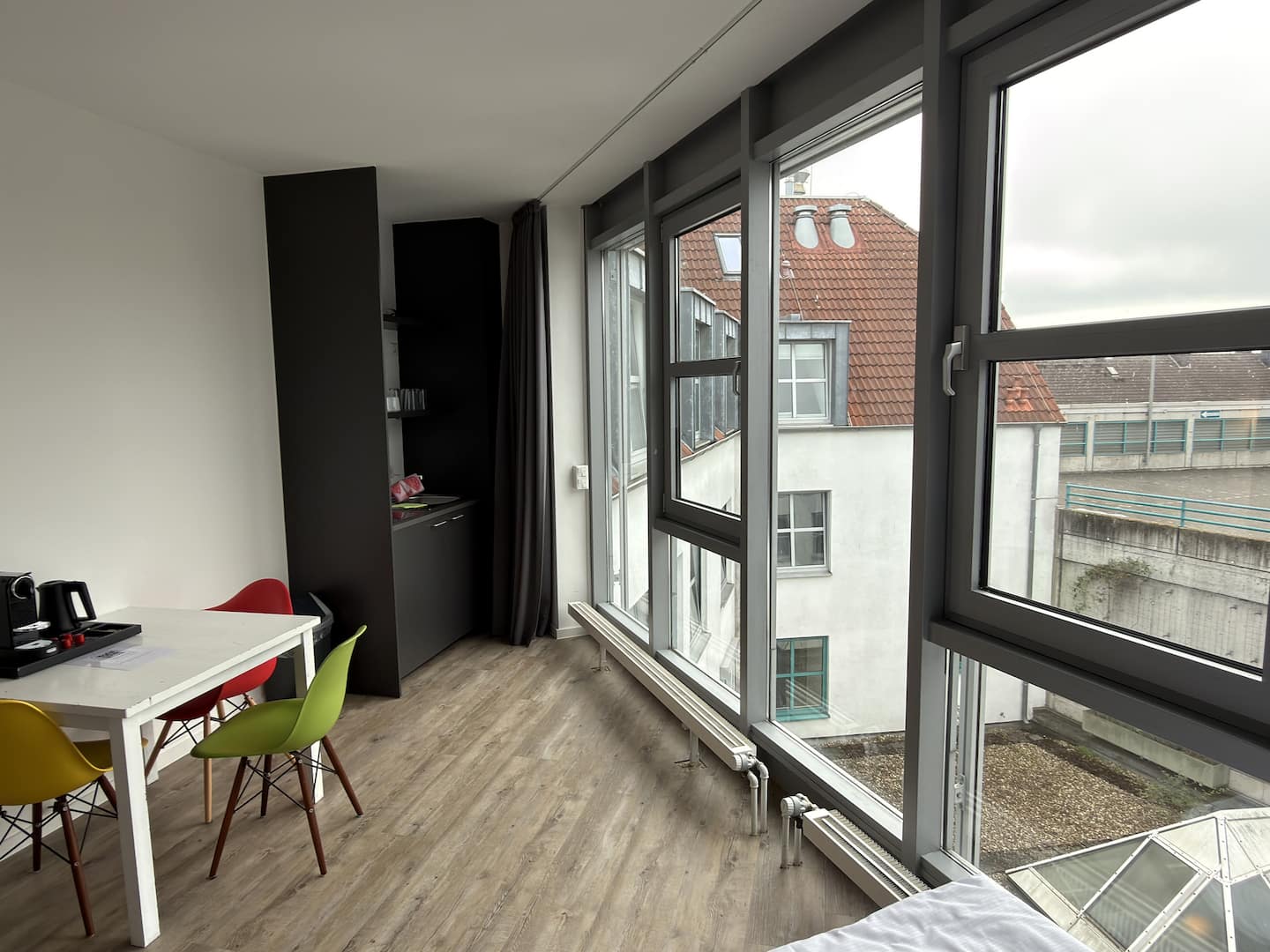 Essplatz mit weißem Tisch und bunten Stühlen am Fenster