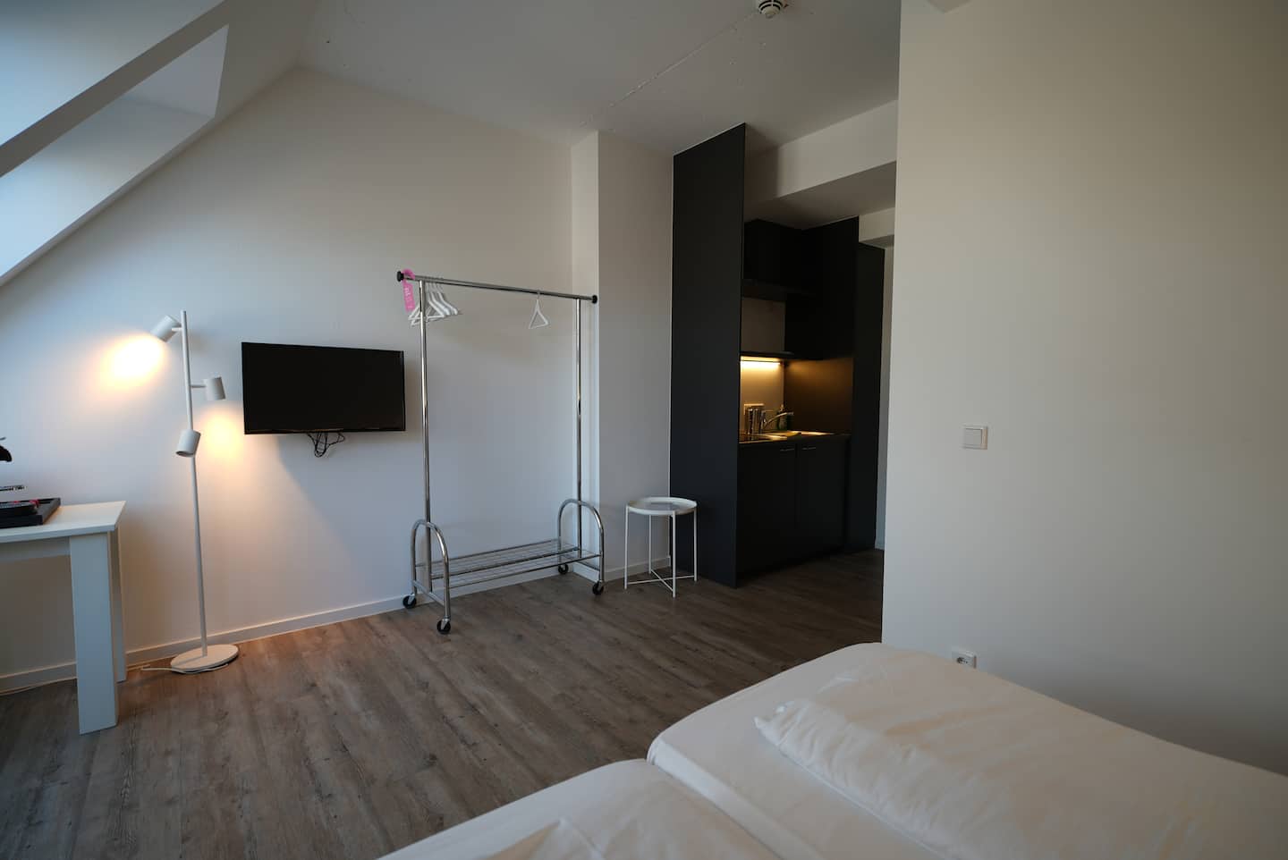 Wohnbereich mit TV, Kleiderstange und Holzboden
