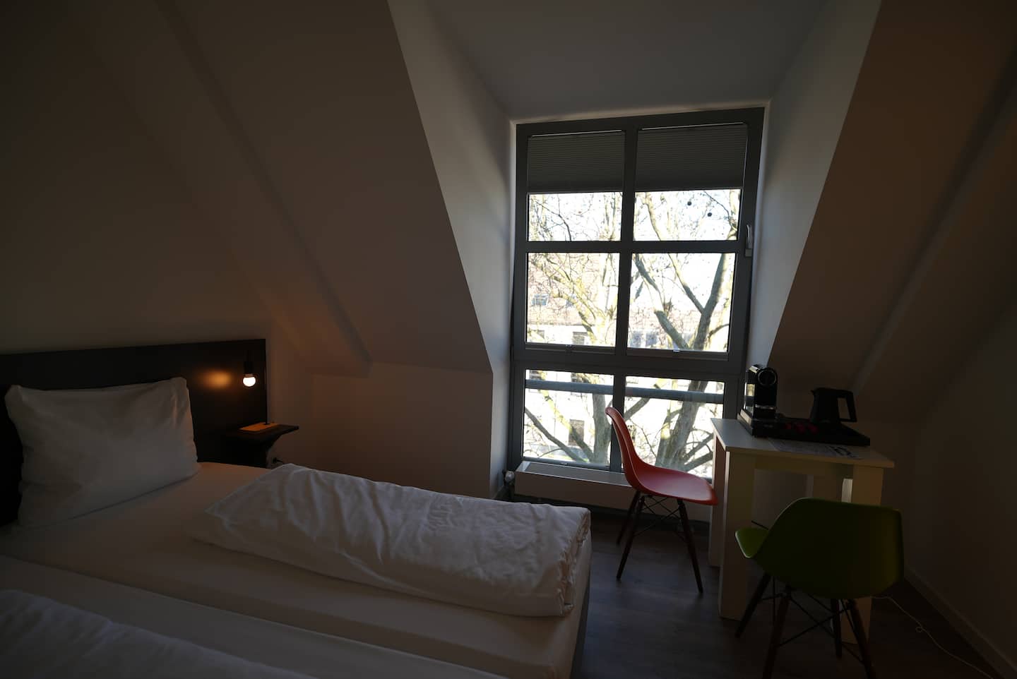 Blick vom Bett zum Fenster mit Tisch und Stühlen