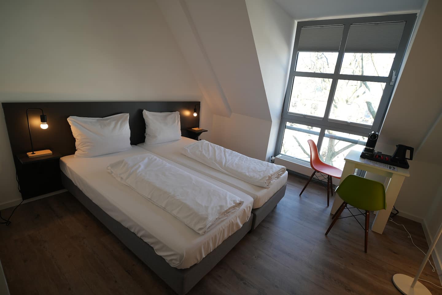 Doppelbett mit dunklem Kopfteil und Sitzecke am Fenster