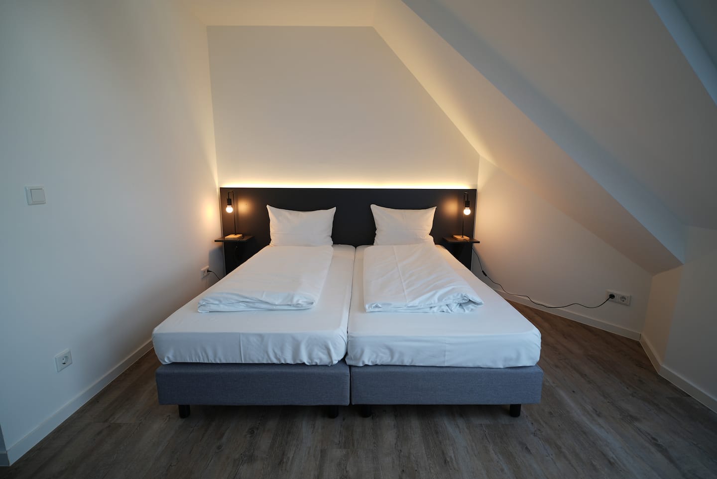 Doppelbett unter der Dachschräge mit beleuchtetem Kopfteil