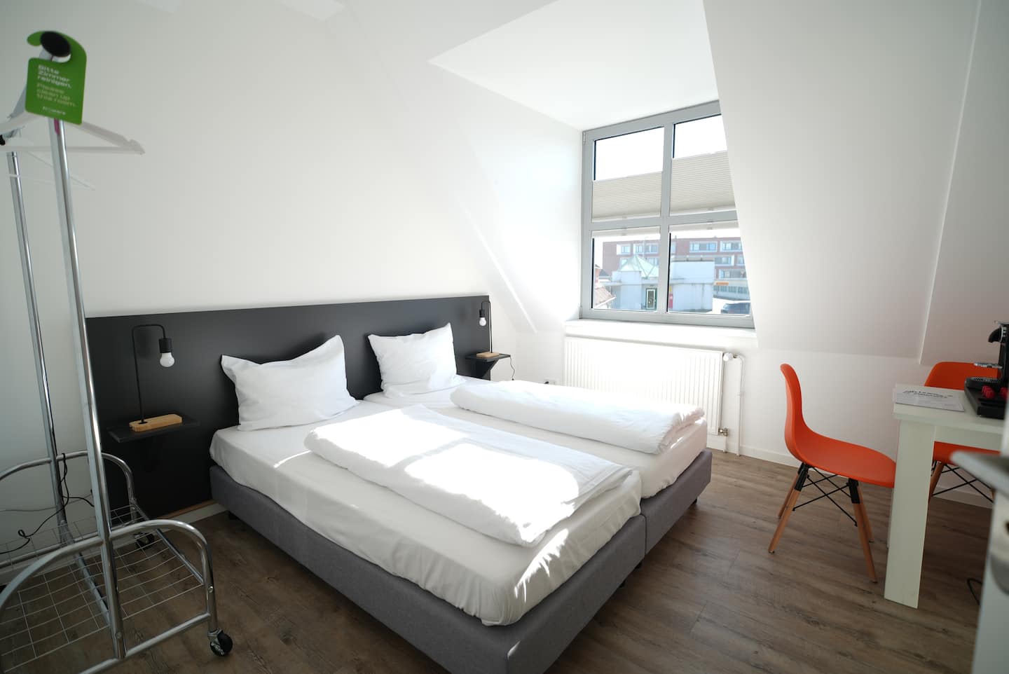 Doppelbett mit dunklem Kopfteil vor hellem Fenster
