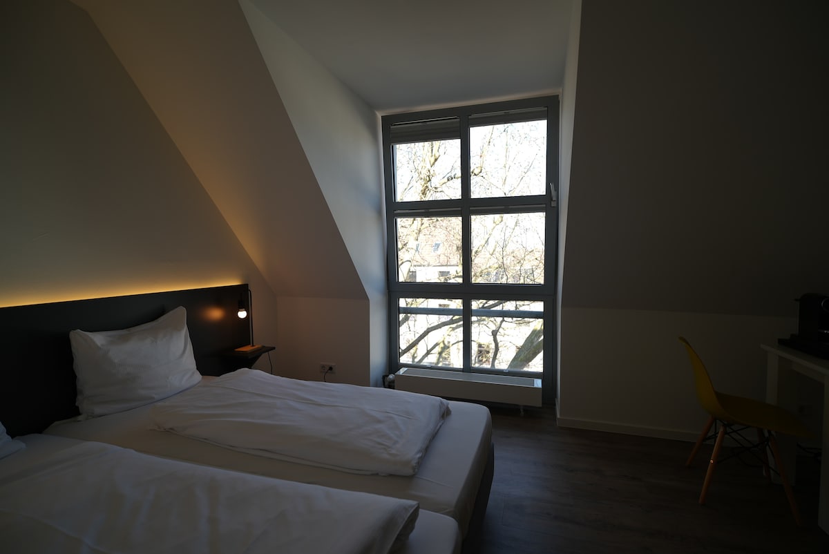 Bett neben einem hohen Fenster mit Tageslicht