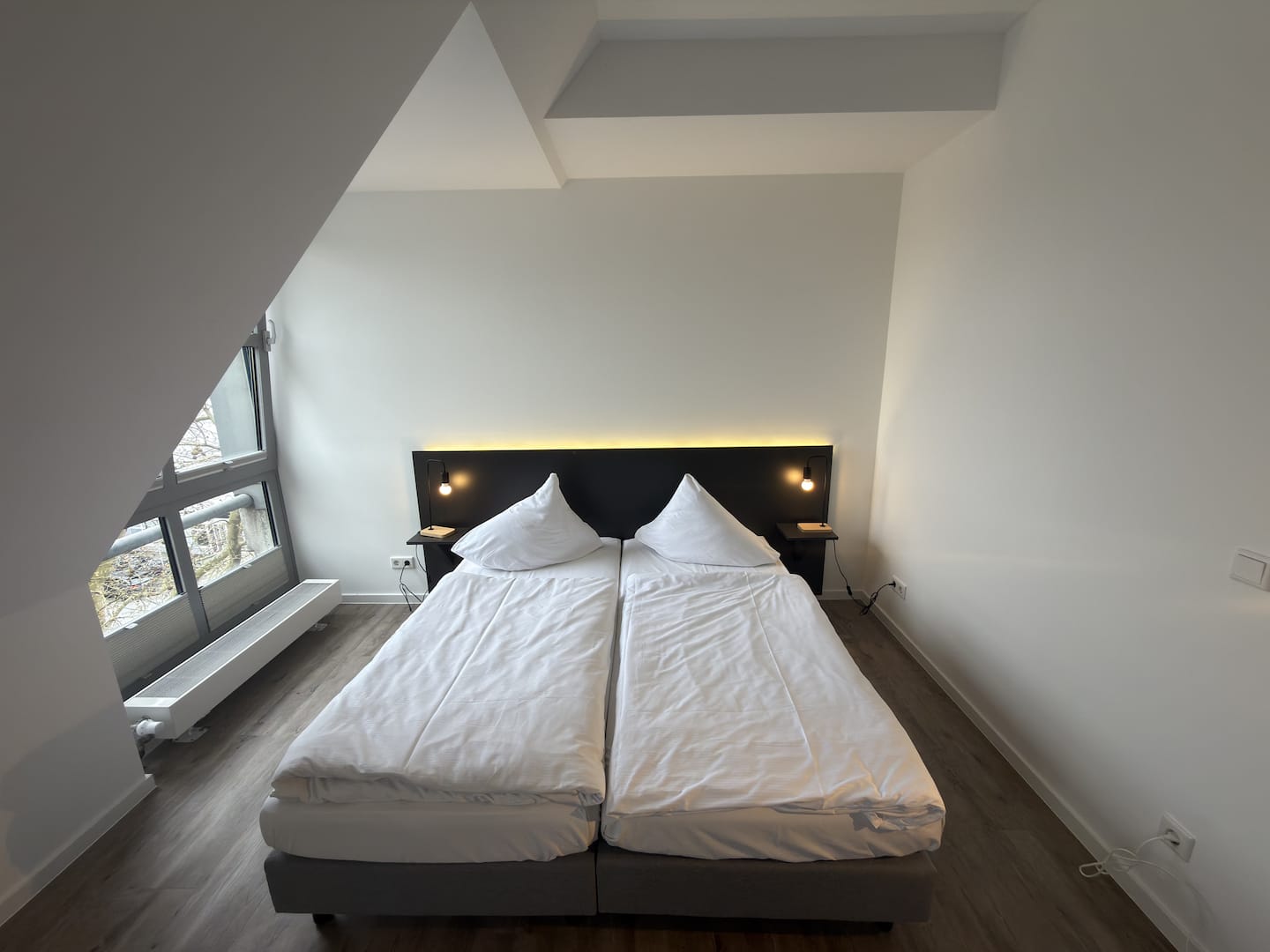 Bett mit weißer Bettwäsche unter der Dachschräge