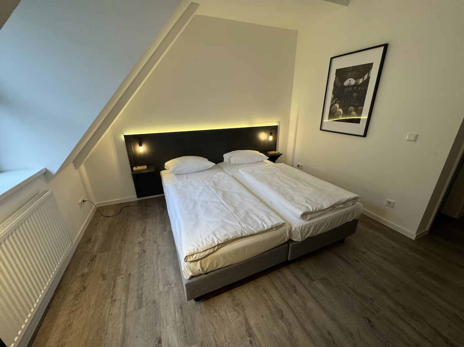 Bett mit Leselampen und Blick zum Fenster