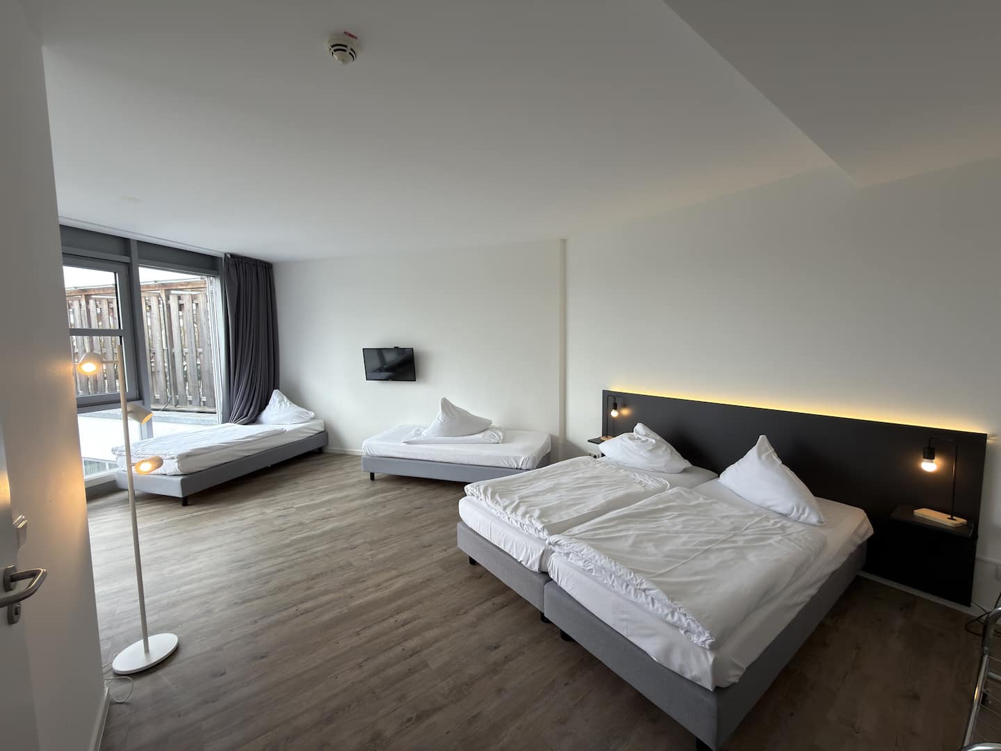 Zimmer mit zwei Betten, Stehlampe und Fenster