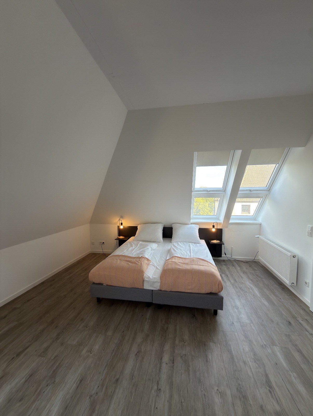 Doppelbett mit weißer Bettwäsche und Leselampen unter der Dachschräge