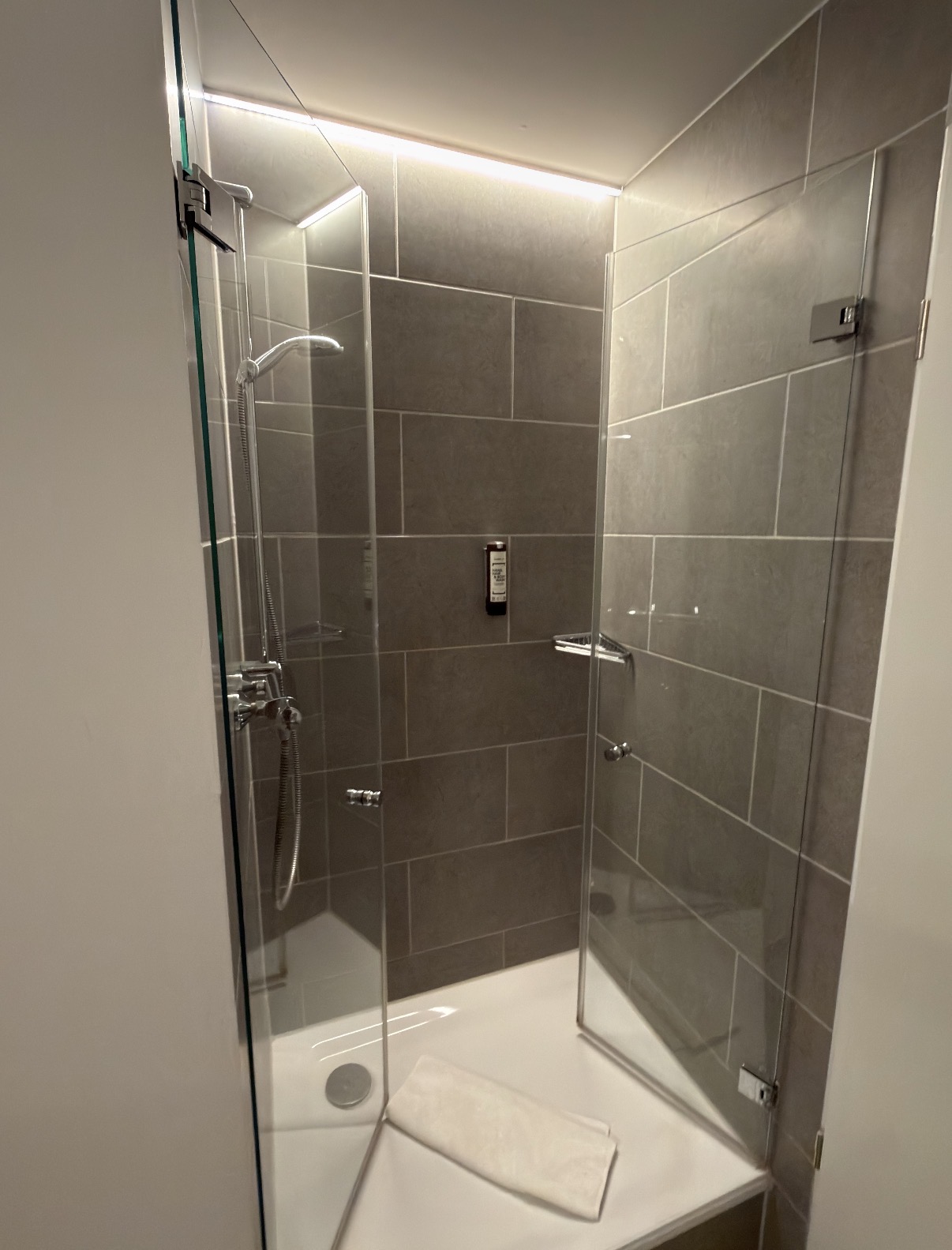 Moderne Dusche mit Glasabtrennung und grauen Fliesen