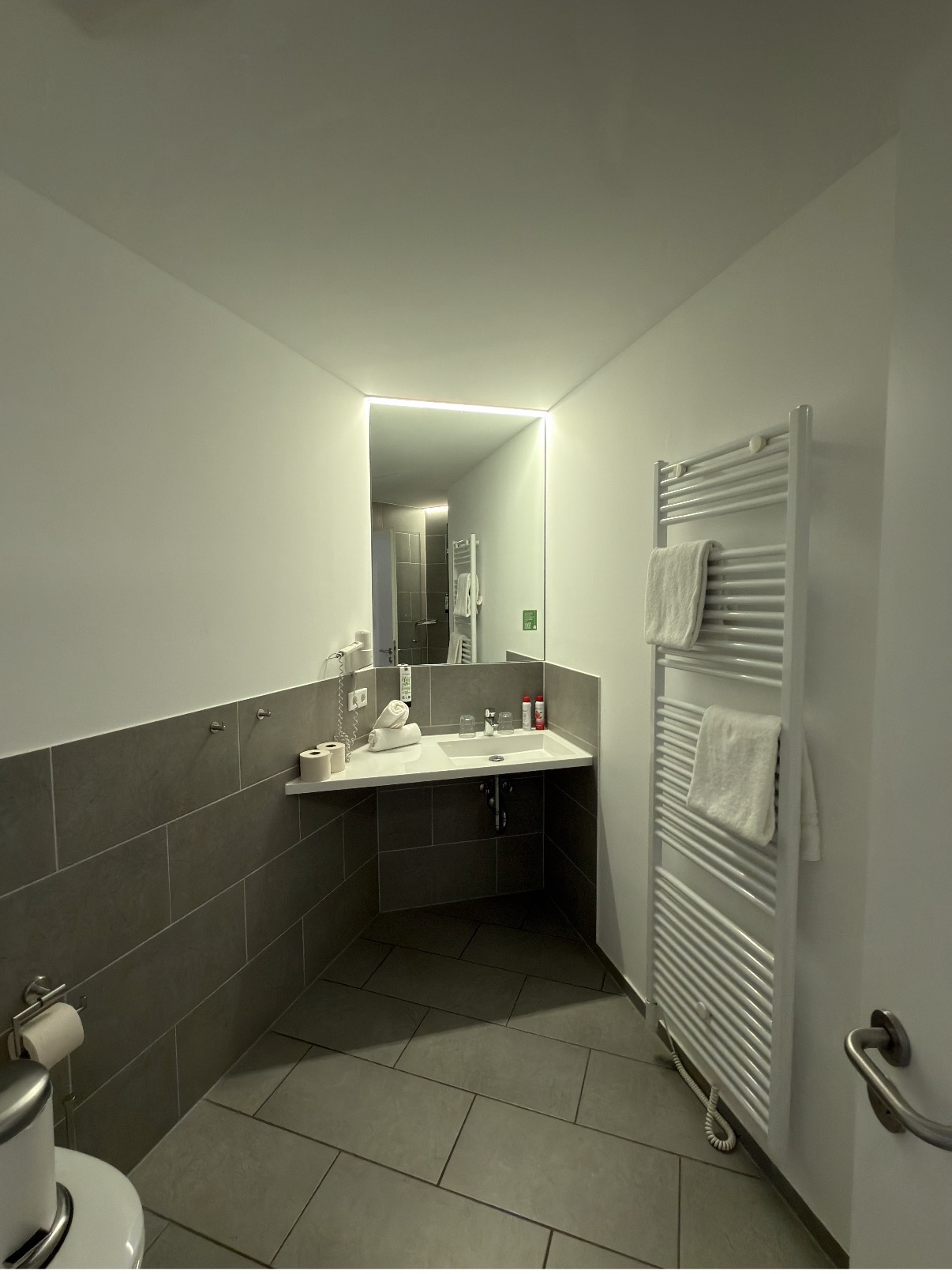 Waschtisch mit Spiegel, Handtuchwärmer und bereitgelegten Handtüchern