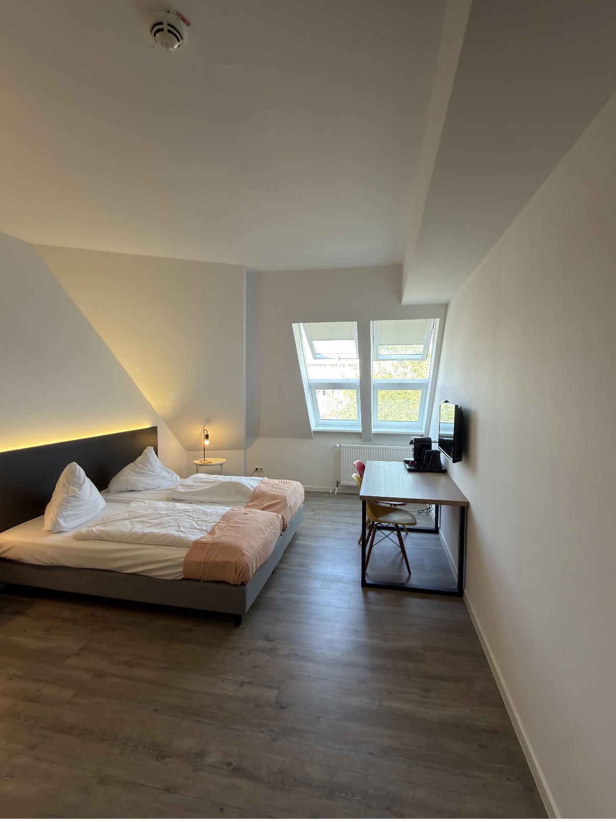 Wohn- und Schlafbereich mit Doppelbett, Arbeitstisch und Fenstern
